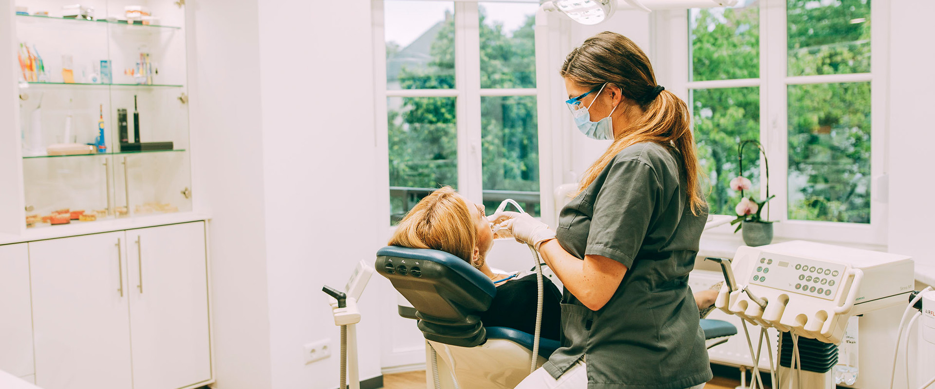 Die Parodontologie in der Zahnarztpraxis Brückner in Dresden: Eine Prophylaxe-ZFA reinigt die Zähne einer Patientin mit einer PZR.
